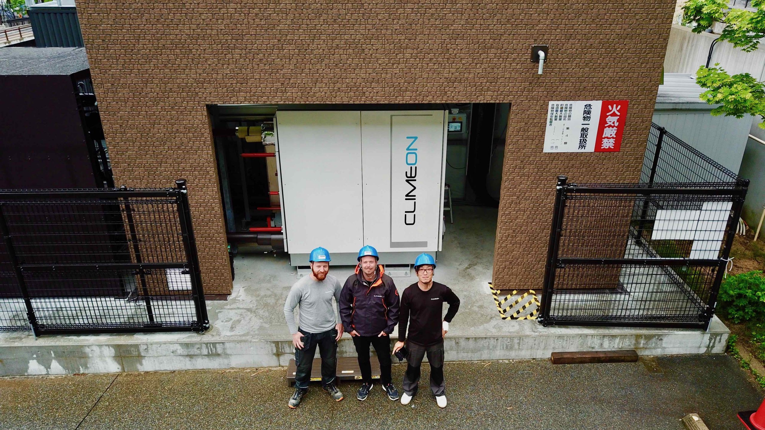 Three Climeon workers standing in front of a HeatPower module on a Japanese power site.